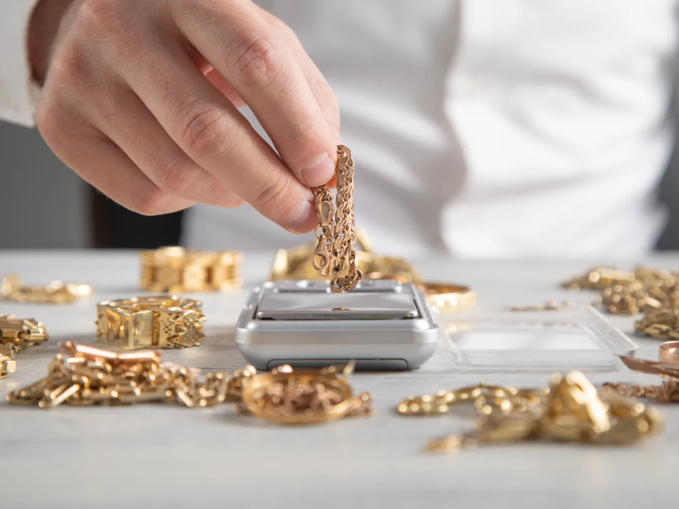 Over a worker's shoulder, a jeweler's loupe is held over the hallmark on a gold ring during the inspection stage of a gold and silver evaluation