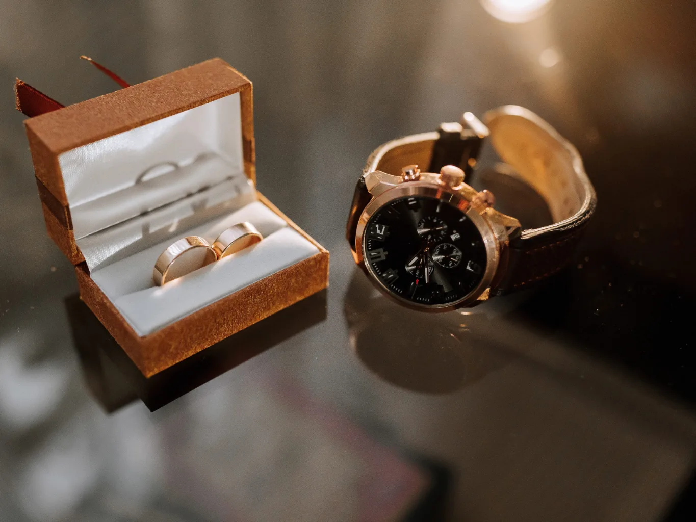 During the intake stage of a watch evaluation, a worker uses a watchmaker's case knife to open the back of a watch resting on a padded tray, with its strap and small parts arranged beside it