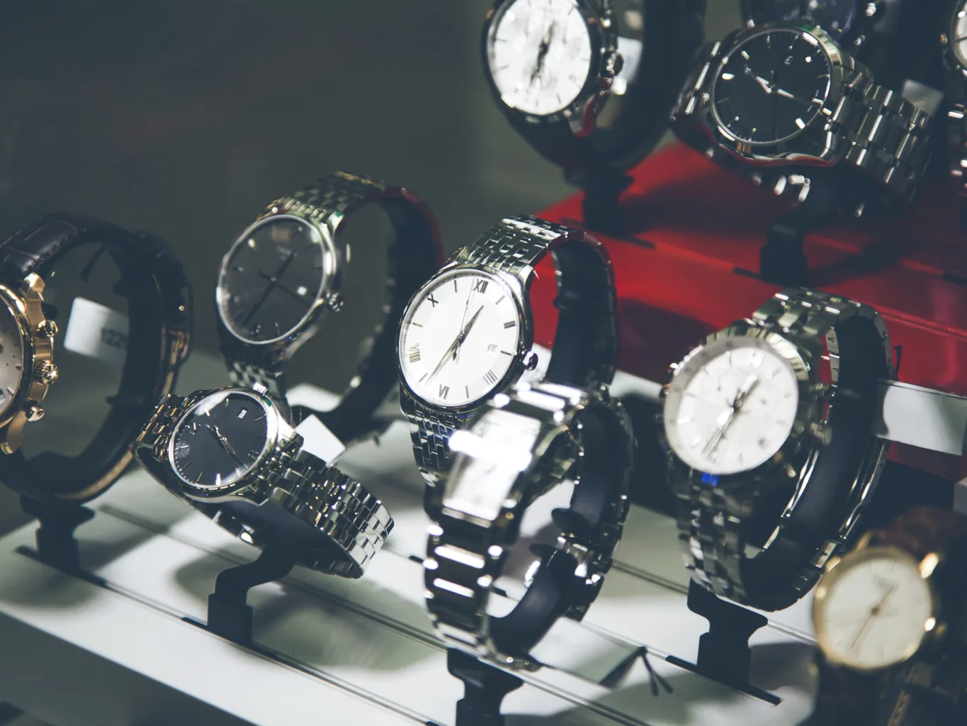 At the condition-review stage of a watch evaluation, a worker uses a watch bracelet pin remover on a Rolex resting on a padded watch tray, with the bracelet and loose pin arranged beside it
