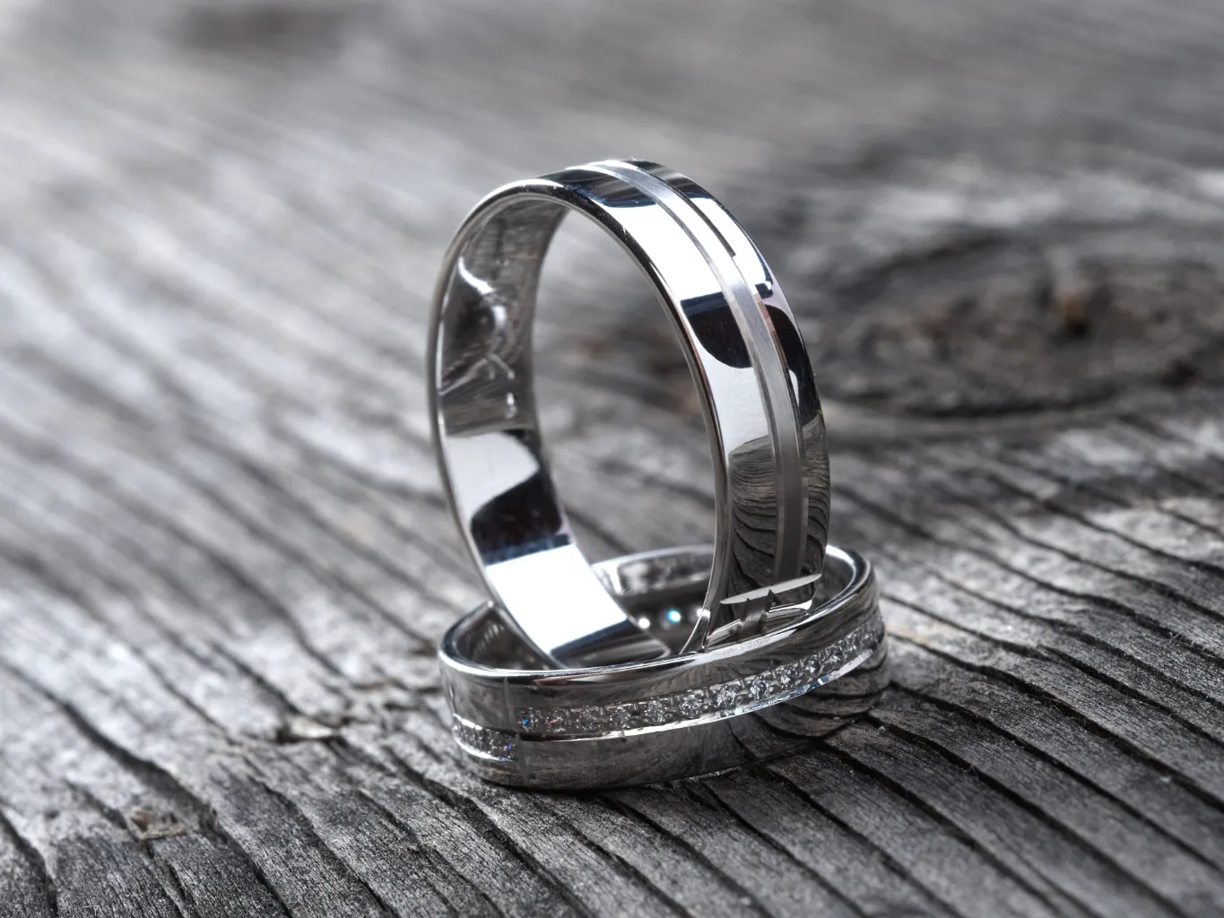 During the condition-review stage of a platinum ring evaluation, a worker uses jeweler's tweezers to lift a small ring above a dark tray and examine its underside